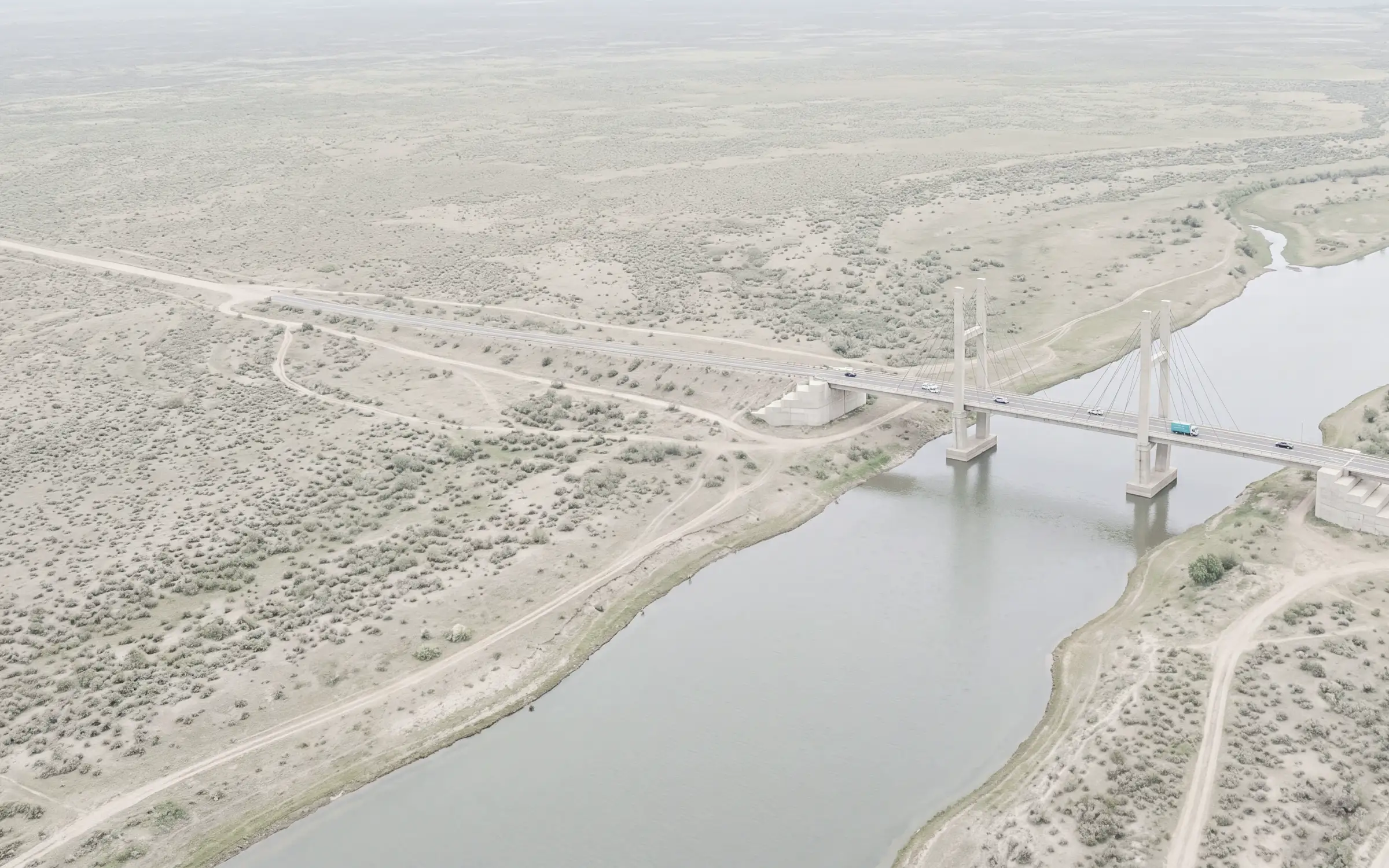 AI-generated scene: a cable stayed road bridge over a calm river, seen from the air.