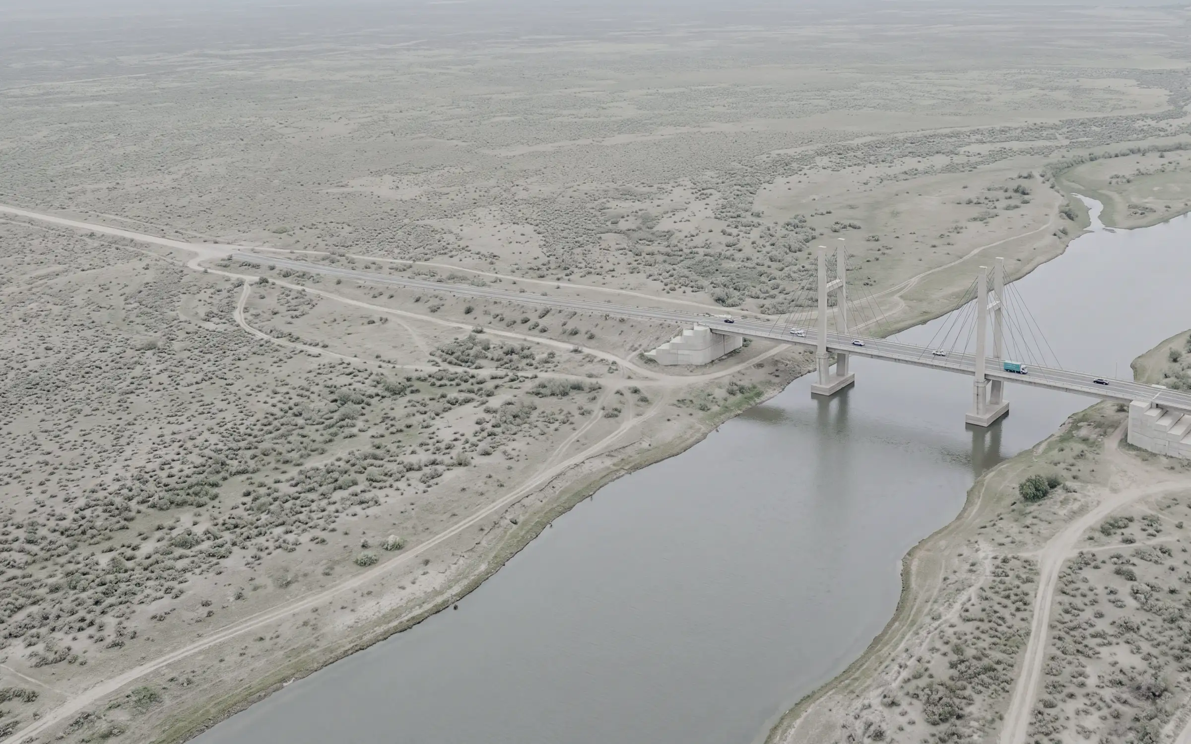 AI-generated scene: a cable stayed road bridge over a calm river, seen from the air.